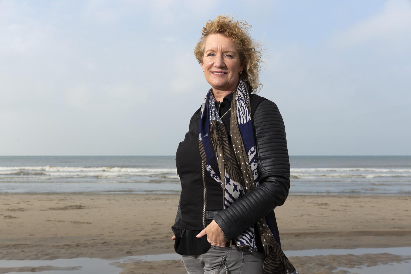 Een foto van Monique van der Veer op het strand. De foto is gemaakt voor een artikel in de serie RvIG'er in beeld