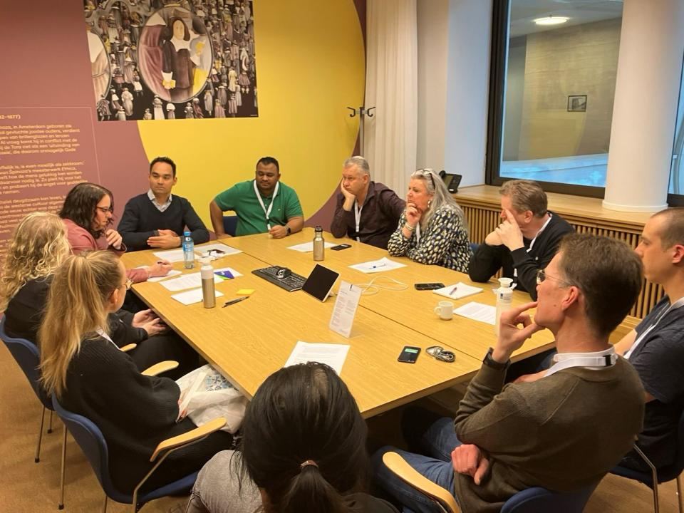 Grote groep LAA collega's zitten aan een tafel tijdens een bespreking